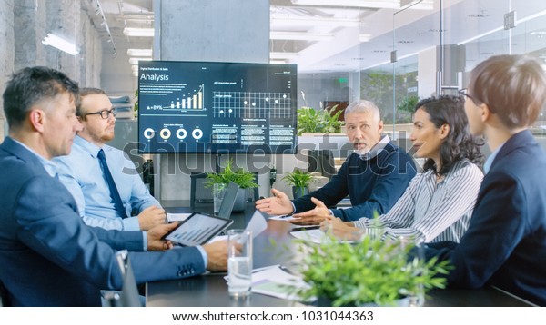 Board\
of Directors Has Annual Meeting, Diverse Group of Business People\
in the Modern Conference Room Discuss Statistics and Work Results.\
In the Background Projector Showing Company\
Growth.