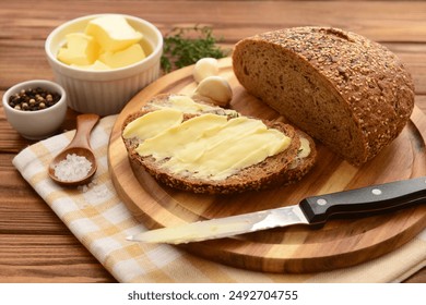 Board with fresh bread, different spices and bowl of butter on wooden background - Powered by Shutterstock