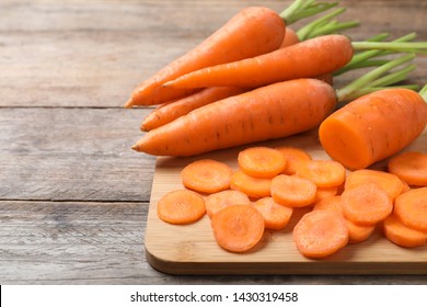 Board with fresh and cut carrots on wooden background. Space for text - Powered by Shutterstock