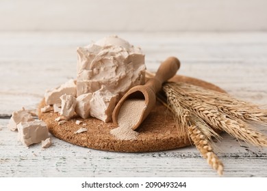 Board with fresh and dry yeast on light wooden background