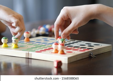 Board game with children hand, colorful figures and red die.