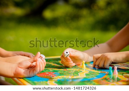 Board game and kids leisure concept. Kids are playing. people holding figures in hand. yellow, blue, green and red wood chips in children play.concept of board games. Dice, chips and cards. Party
