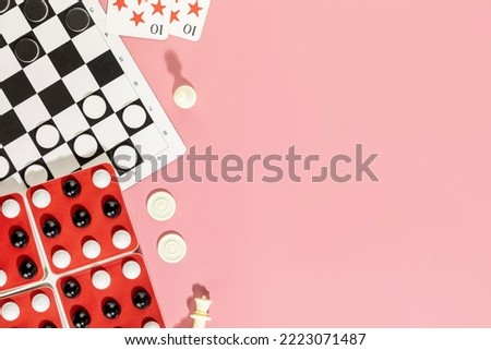 Board games background. Various board games  with chess pieces, checkers and playing cards on a pink background copy space. Vacation at home with family. Flat lay