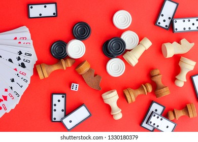 Board games on a red background: playing cards, dominoes, checkers and chess. the view from the top