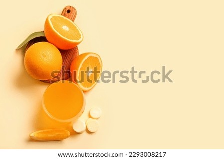 Board with glass of vitamin C effervescent tablet dissolved in water and oranges on beige background