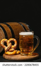 Board with mug of beer, pretzels and barrel on table against dark background. Oktoberfest celebration