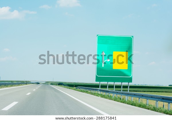 Board on the right side of high way with\
yellow and green space for\
directions
