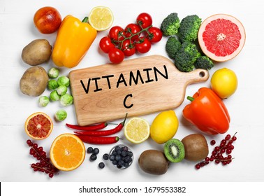 Board with phrase VITAMIN C and fresh products on white wooden table, flat lay