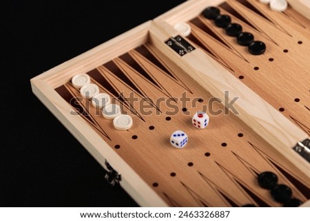 Board for playing backgammon with pieces and dice on a black background. Board game, pastime, fun.