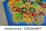 Board strategic economic game Catan top view playing field with chips and tiles, red, blue, orange road and cities, figures. Concept: board game. relax with friends. fun hobby, strategy. economic game