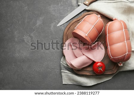 Board with tasty boiled sausages and tomato on grey textured table, flat lay. Space for text