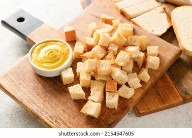 Board with tasty croutons and sauce on white background, closeup