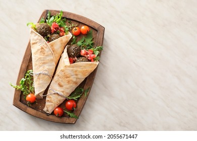 Board with tasty falafel pita on light background