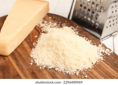 Board with tasty grated Parmesan cheese on light wooden background, closeup - Powered by Shutterstock