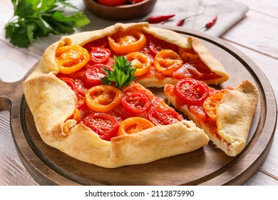 Board with tasty tomato galette on light wooden background, closeup - Shutterstock ID 2112875990