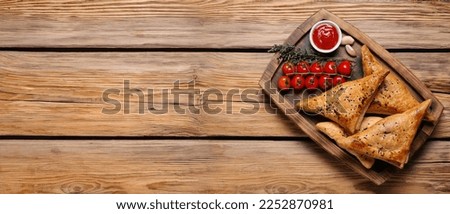 Board with tasty Uzbek samsas and tomatoes on wooden background with space for text