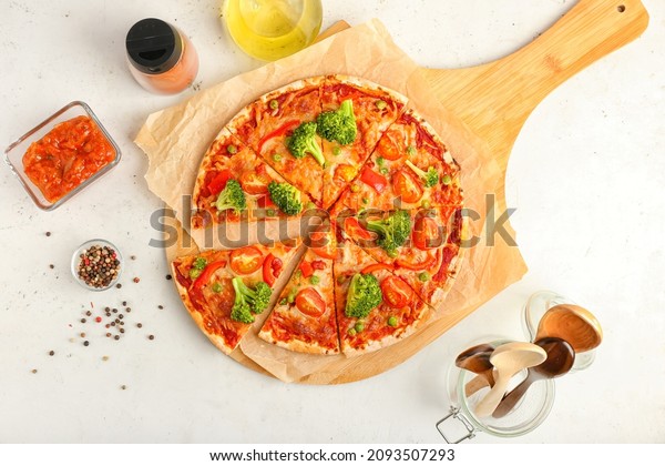 Board with tasty vegetarian pizza, sauce and
peppercorn on light
background