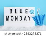 Board with text BLUE MONDAY, sad face, umbrella and snow