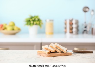 Board With Toasts And Knife On Table In Modern Kitchen