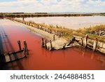 Board walks running through the pools of the Burgas Salt Pans, filled with pink water, the clouds in the sky reflected in the water, Lake Atanasovsko, Atanasovo, Burgas, Bourgas, Bulgaria 2022