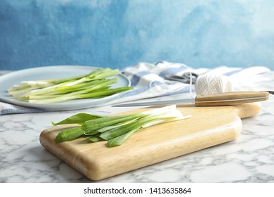 Board with wild garlic or ramson on marble table against color background. Space for text