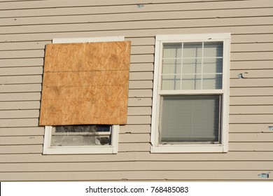 Boarded Up Window And Hail Storm Damage On House Siding And Window Frame