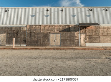 A Boarded-up Storefront Wall Overlooking A Vacant Lot. 