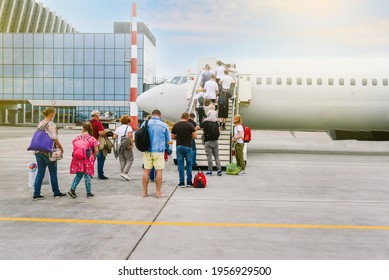 Boarding Passengers On The Plane. People With Luggage Go Up The Stairs To The Aircraft Cabin. Passenger Plane. Travel And Tourism Concept. Modern International Airport.