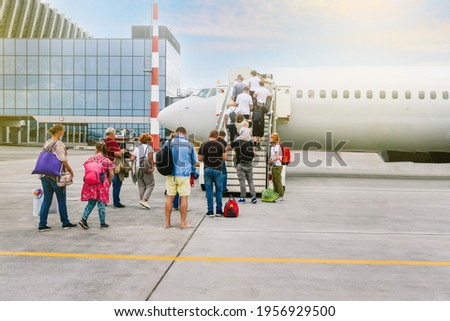Boarding passengers on the plane. People with luggage go up the stairs to the aircraft cabin. Passenger plane. Travel and tourism concept. Modern international airport.