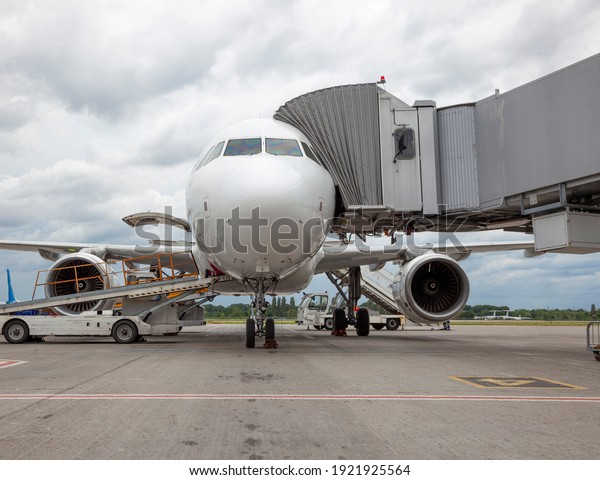 Boarding passengers on the\
plane through the boarding bridge. The plane lands at the\
international airport. Loading luggage. White airplane. Terminal\
Runway