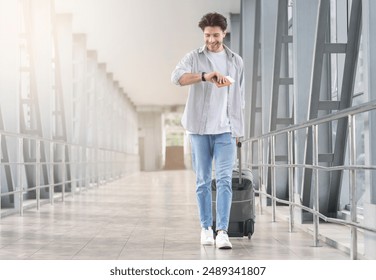 Boarding Time. Happy man checking time on watch, walking with suitcase in airport, going to departure gate, free space - Powered by Shutterstock