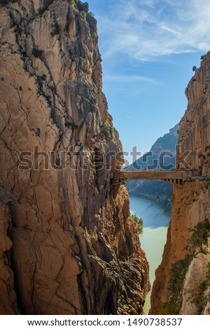 Boardwalk and footbridge of 'Caminito del Rey' mountain walk and hiking route.  Bridge between two steep mountains over the canyon and lake in the background. Path along steep cliffs. Andalusia, Spain
