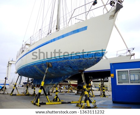 A boat in a boatyard, pleasure sailing craft supported on the hardstand, annual boat maintenance.