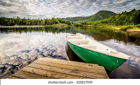 Boat by deck on a lake in National Park Mont Tremblant, Canada. Travel, explore, adventure, vacation, summer, wilderness, retirement, fishing and concept. Widescreen 16:9 aspect ratio wallpaper
