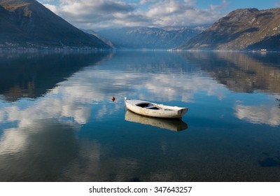 boat in calm clear full of sky water with mountains background
