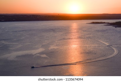 A Boat Catches The Last Rays Of Sunlight Over Lake Travis In The Hill Country Of Central Texas.