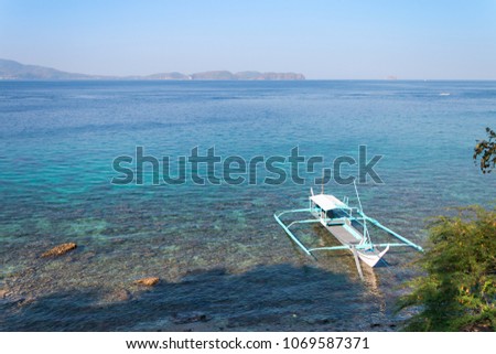 Boat for diving-trips docked over coral reef in Batangas, Philippine.