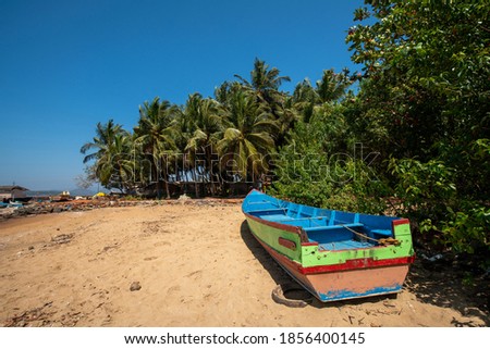 Boat in fishing village in Kumta district. Coconut pam trees along coastline and boats