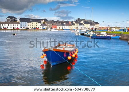 Boat in Galway Bay in front of old Galway Town and it's pastel buildings.