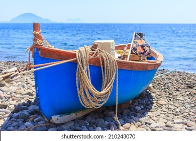Boat, with hanging rope, docked on shore