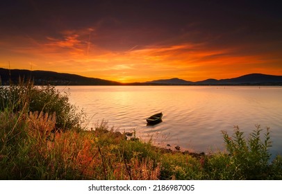 Boat in the lake at sunset. Sunset lake boat. Lake boat at sunset. Boat in lake at sunset
