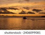 Boat launching at sunrise. Orange hour. Takapuna Beach, Auckland, New Zealand. 