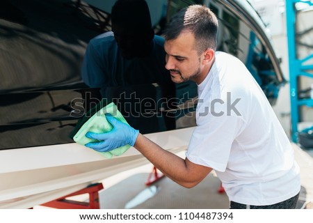 Boat maintenance - A man cleaning boat with cloth. Selective focus.