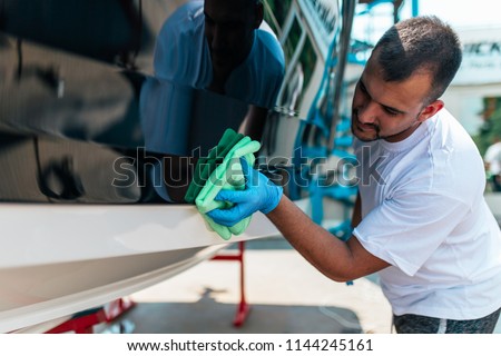 Boat maintenance - A man cleaning boat with cloth. 