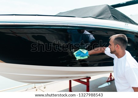 Boat maintenance - A man cleaning boat with cloth. Selective focus.