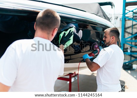 Boat maintenance - Two men polishing boat. Selective focus.