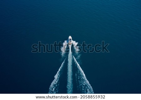 Boat movement on blue water top view. White speed boat fast movement on the water top view. Travel - image. Top view of a white high-speed boat.