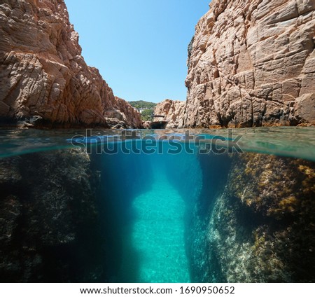 Boat in a narrow passage on rocky coast, split view over and under water surface, Mediterranean sea, Spain, Costa Brava, Catalonia
