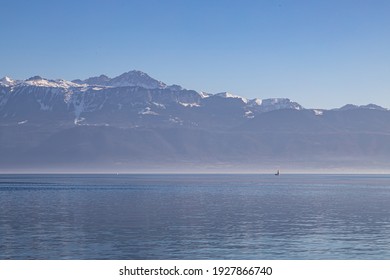 A boat on hazy, misty Lake Geneva and the Alps seen from Lausanne, Switzerland - Powered by Shutterstock