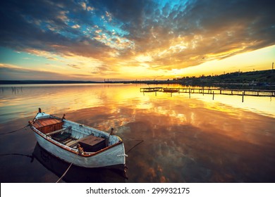 Boat On Lake With A Reflection In The Water At Sunset